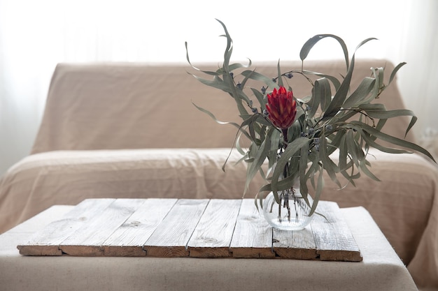 A modern, minimalist living room decorated with upcycled furniture: a coffee table made from reclaimed wood pallets, lamps made from repurposed glass bottles, and cushions made from old jeans. The room is bright and airy, showcasing how upcycling can contribute to stylish interior design.