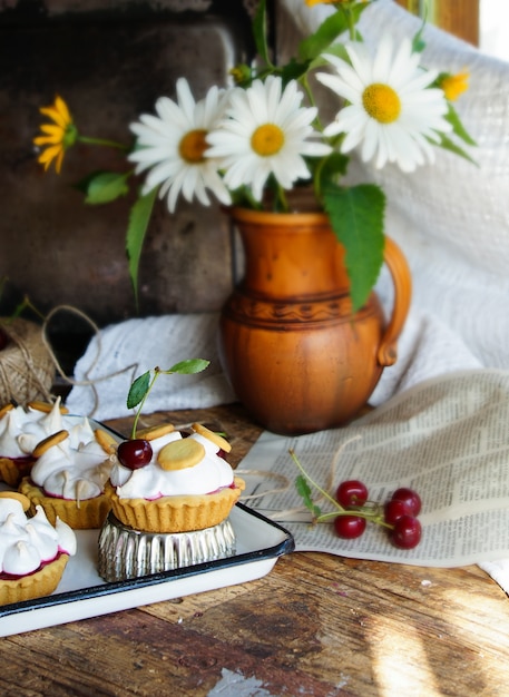 A wooden table set for tea with a linen tablecloth, vintage teacups, and a plate of freshly baked scones. A bouquet of wildflowers sits in the center of the table.