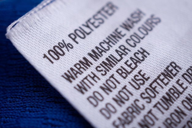 A close-up shot of a garment label displaying detailed information about the fabric composition, manufacturing location, and environmental certifications, such as GOTS or Fair Trade. QR codes are present on the label, linking to more in-depth information online.