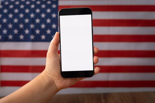 A close-up of a veteran's hand holding a digital coupon on a smartphone, with the American flag subtly blurred in the backdrop. The focus is on the veteran using the coupon in a digital context.
