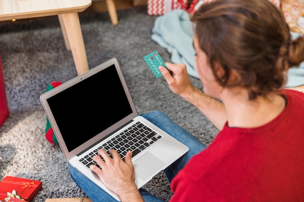 A close-up shot of a person's hands using a laptop to browse online deals and apply coupon codes during a January sale. The screen highlights discount percentages and promo code fields.