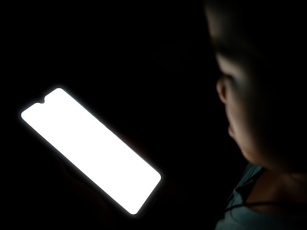 A close-up of a smartphone screen displaying a blurry image of a strange, bright light in the night sky. The phone's camera interface is visible, showing settings and a partially visible hand holding the device.