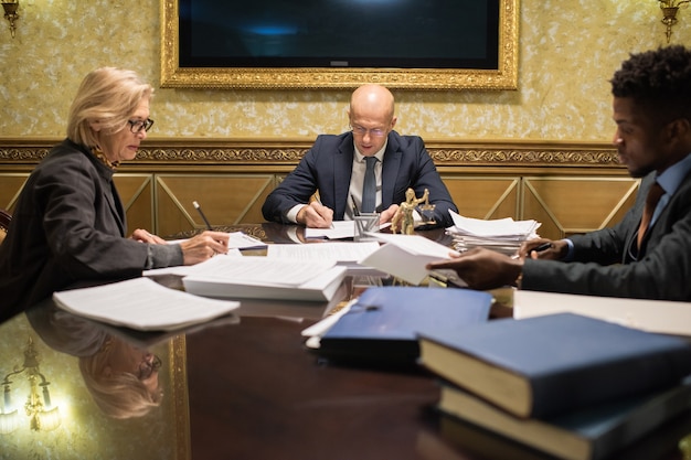 A photograph of government officials in a conference room, reviewing documents and discussing UAP investigations, emphasizing the seriousness and systematic approach to the topic.